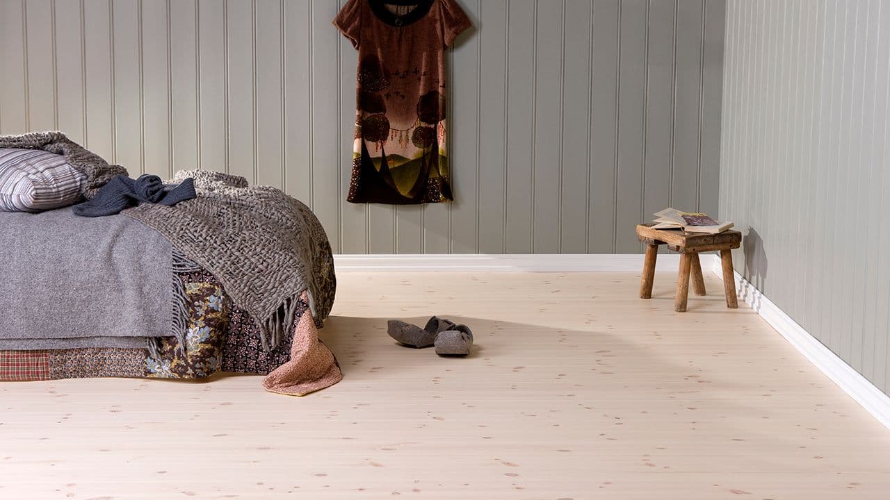 Nærbilde av et oljet heltregulv i furu, med en saks og ruller med hyssing