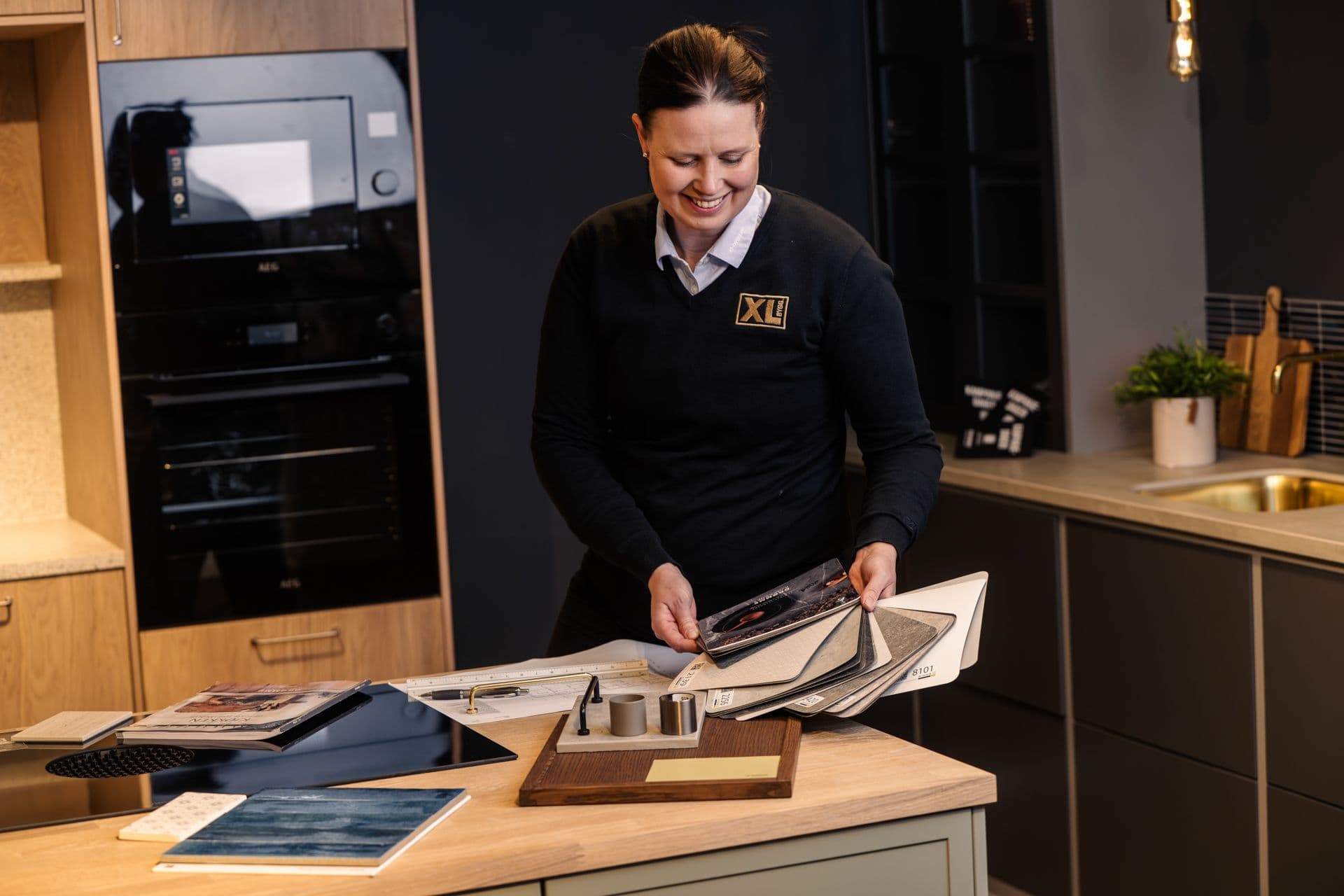 XL-BYGG-ansatt som viser frem valgmuligheter i kjøkkenutstillingen.