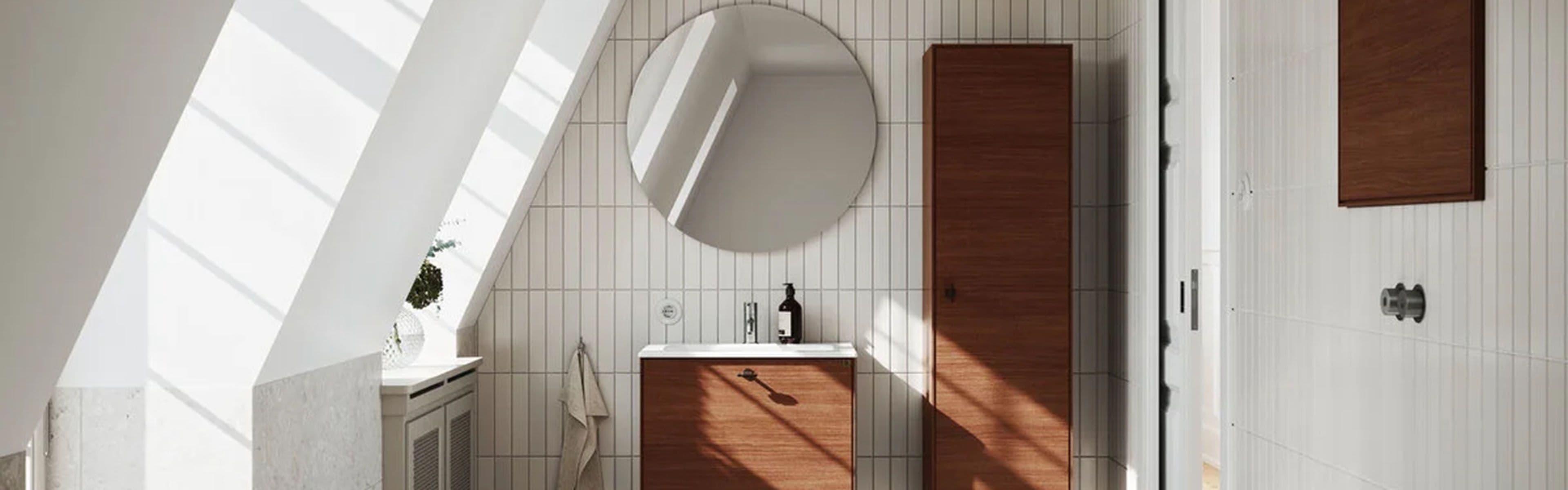 Bad med baderomsmøbler i mørk eik og lyse fliser i steinmønster på vegger og gulv.