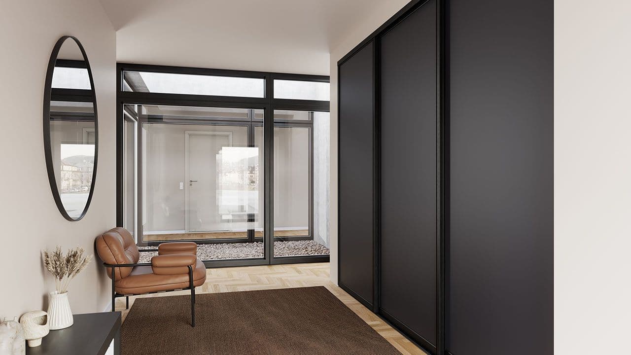 Sort garderobeskap med skyvedører i entre.