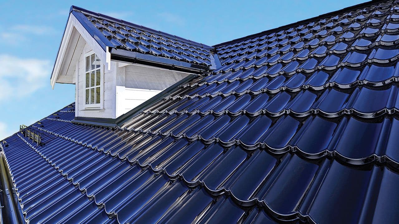 Nærbilde av svarte glatte takpanner i stål på hvitt hus.