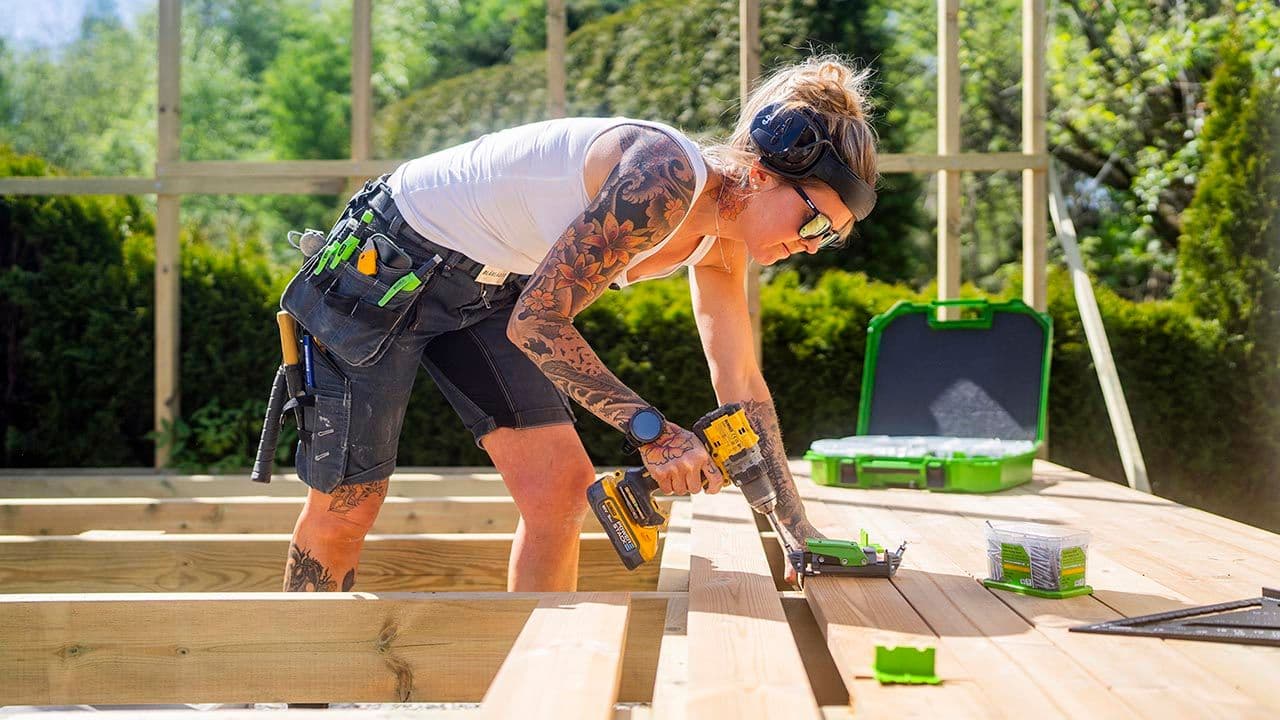Kvinnelig håndverker viser skjult innfesting av terrassebord.