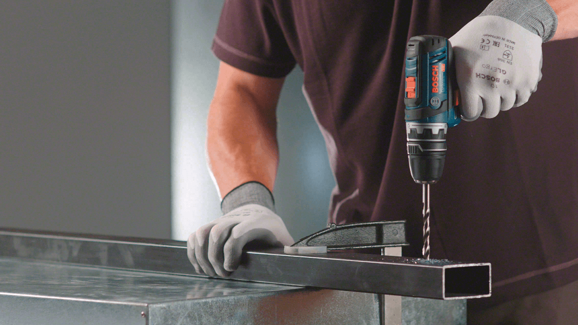 En mann borer i metall med en Bosch drill