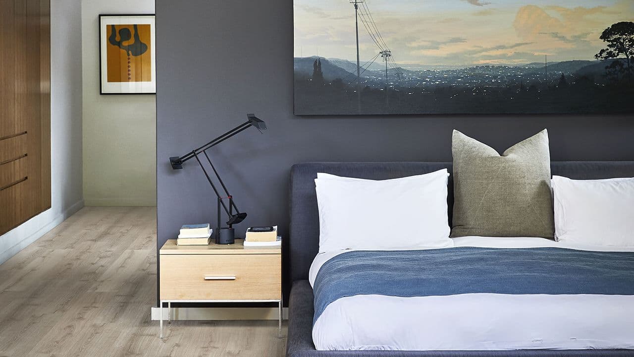 Soverom med mørkeblå skillevegg som sengegavl som gir hotellfølelse på soverommet.