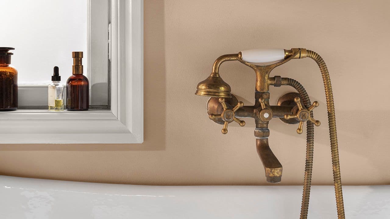 Nærbilde av vegg i baderom med veggmontert dusjarmatur. Vegg malt med LADY Aqua i fargene 12083 Devine og 1624 Letthet.