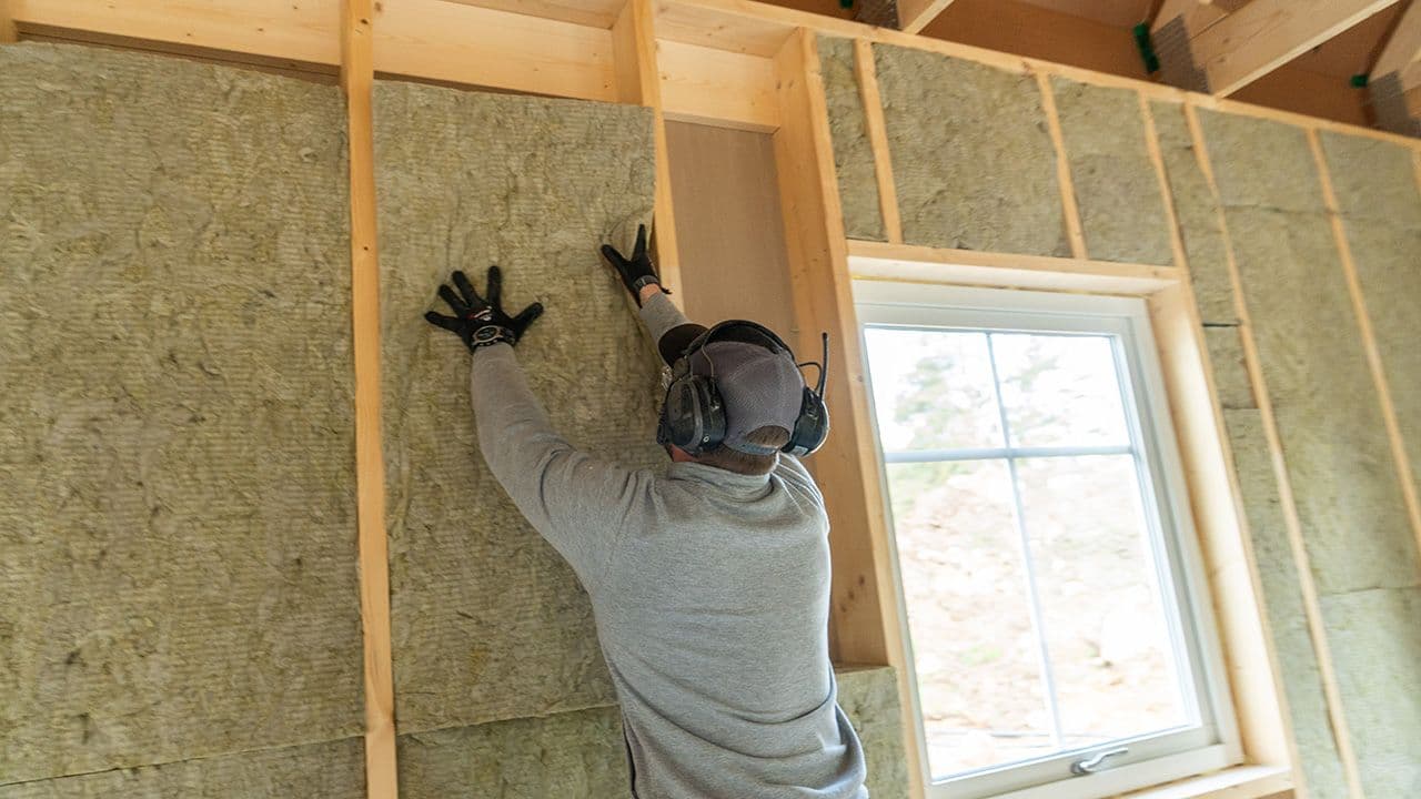 Håndverker som putter isolasjon i veggen.