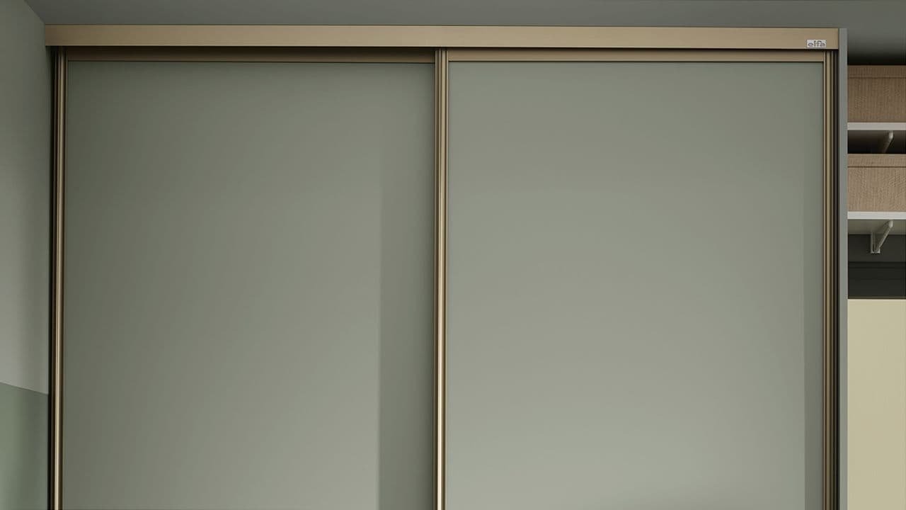 Skyvedørsgarderobe med grønne skapdører og messing-innramming.