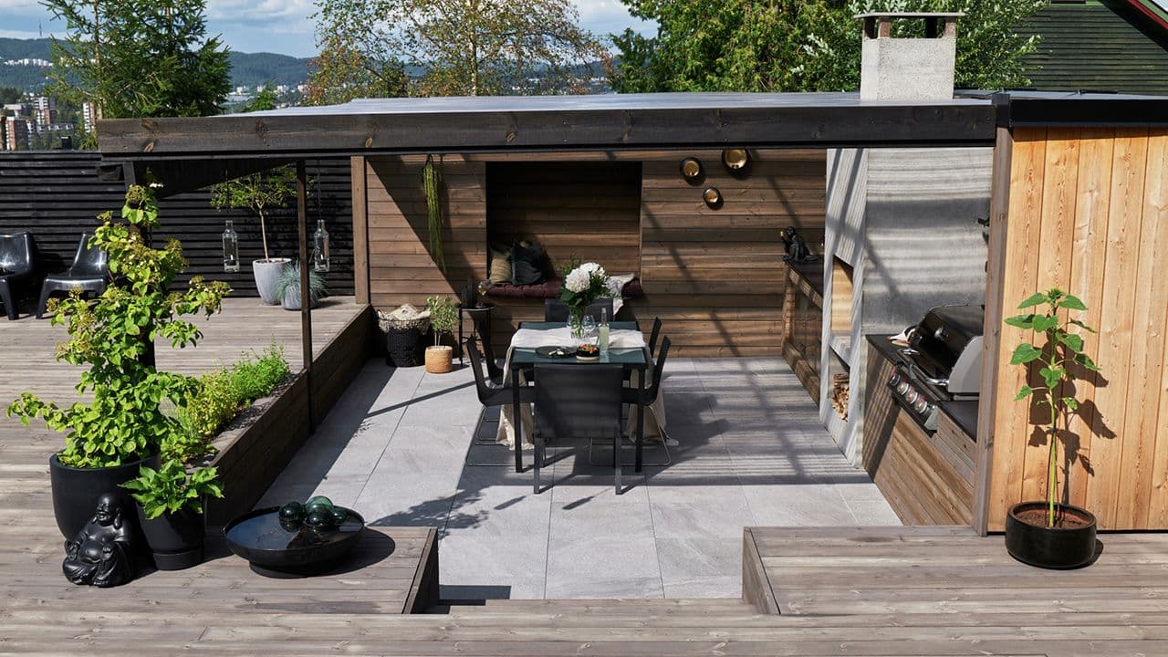 Uteplass med ulike nivåer og terrasse med utekjøkken, spiseplass og tak over.