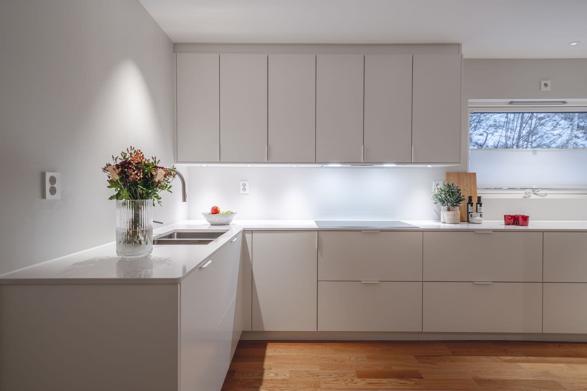 Hvitt kjøkken med hvit benkeplate i L-form.