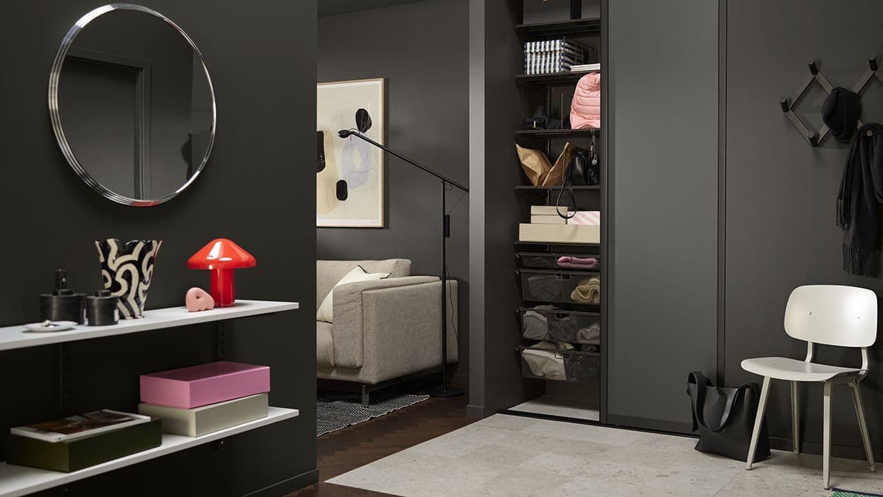 Svart entré med svart skyvedørsgarderobe for oppbevaring i gang.