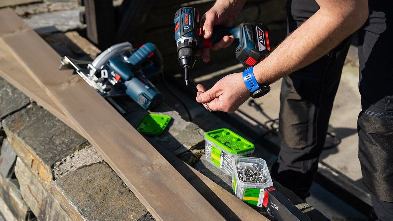 Person med batteridrill fra Bosch i hendene.