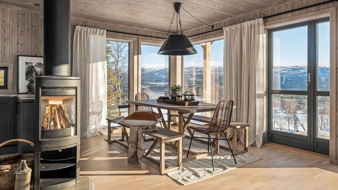 Hytte med panoramavinduer på fjellet.