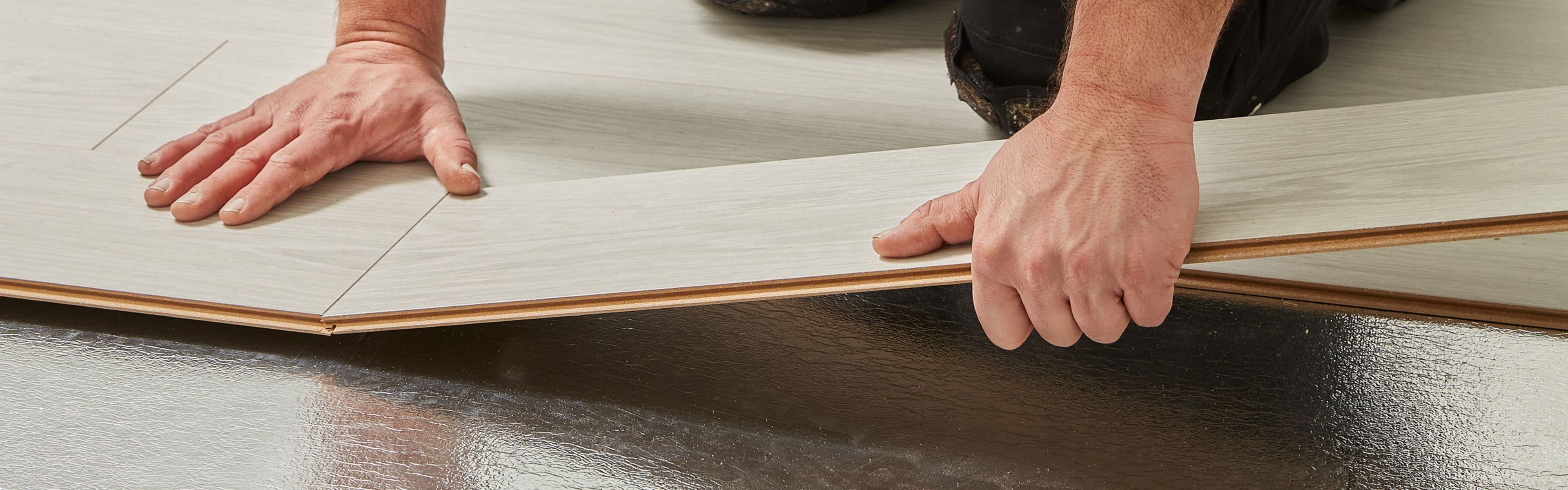 Mann som legger gulv på gulvunderlag.