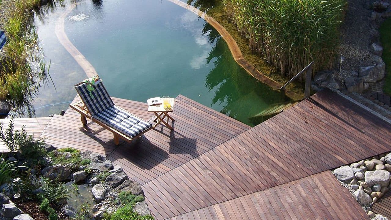 Trinnvis terrasse av termoask med solstol og stor utedam
