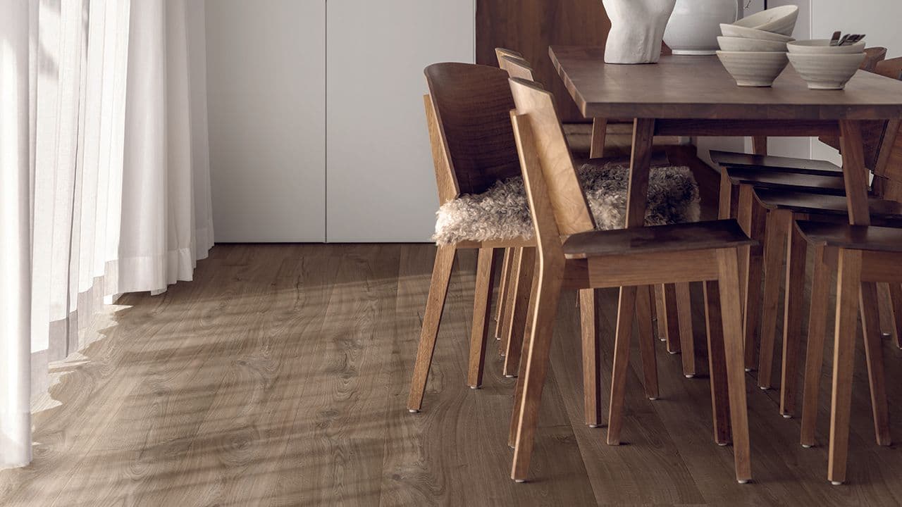 Mørkt laminatgulv i spistestue med store vinduer.