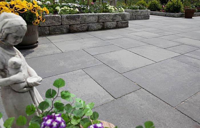 Hageheller på stor uteplass med hagemur som danner blomsterbed.