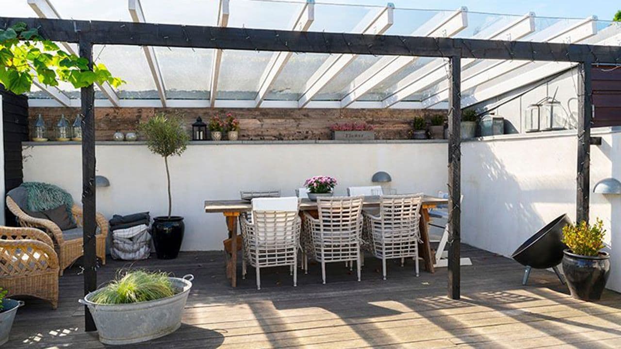 Tak over terrasse med spiseplass og mur.