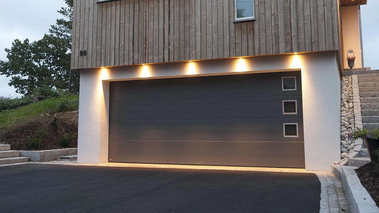 Garasje under hus med sort garasjeport.