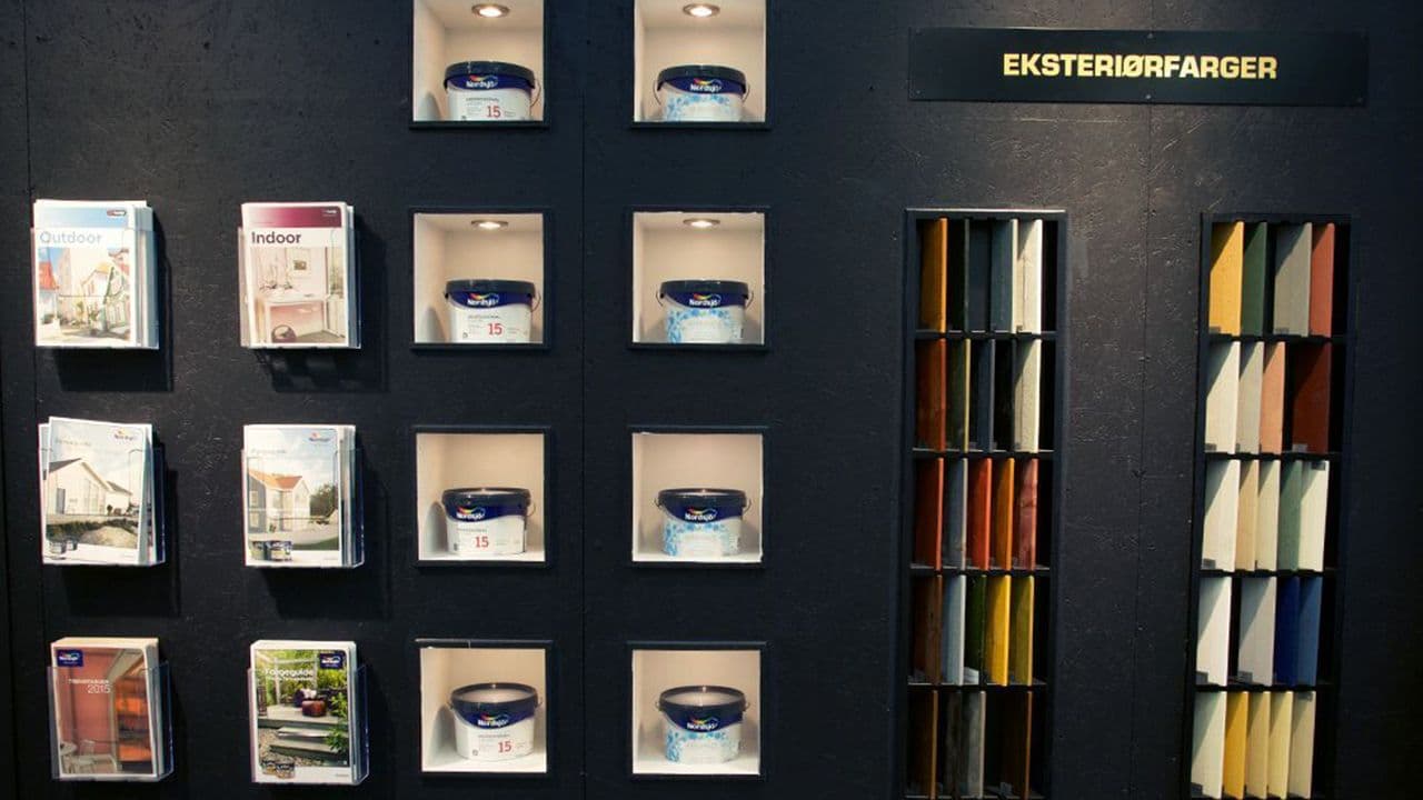 Vegg i butikk hos XL-BYGG med fargekart og -prøver for både dekkbeis eller maling.