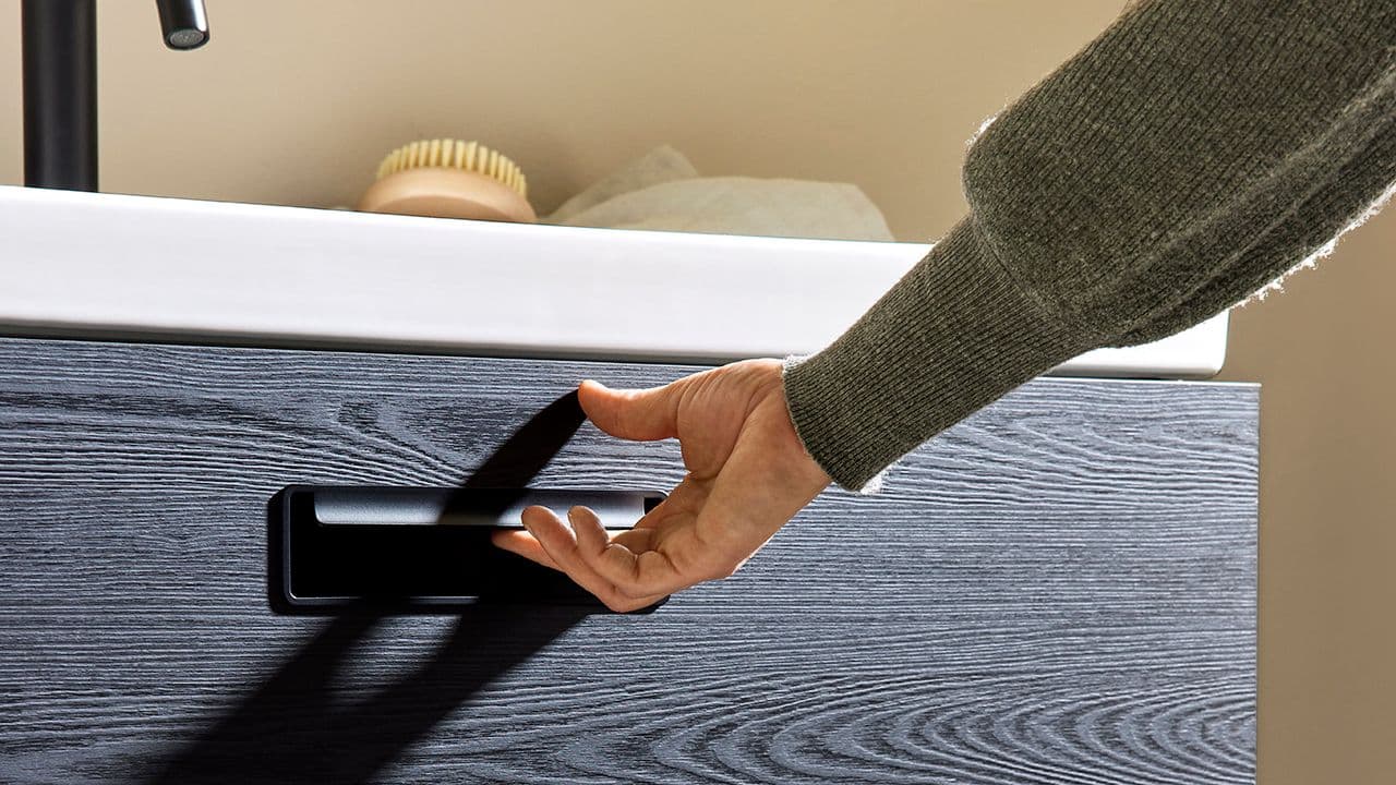 Hyttebad med svart servantskap med trefinish og skuffer.