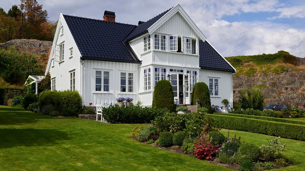 Hvitt hus på to etasjer med stor hage malt med maling.
