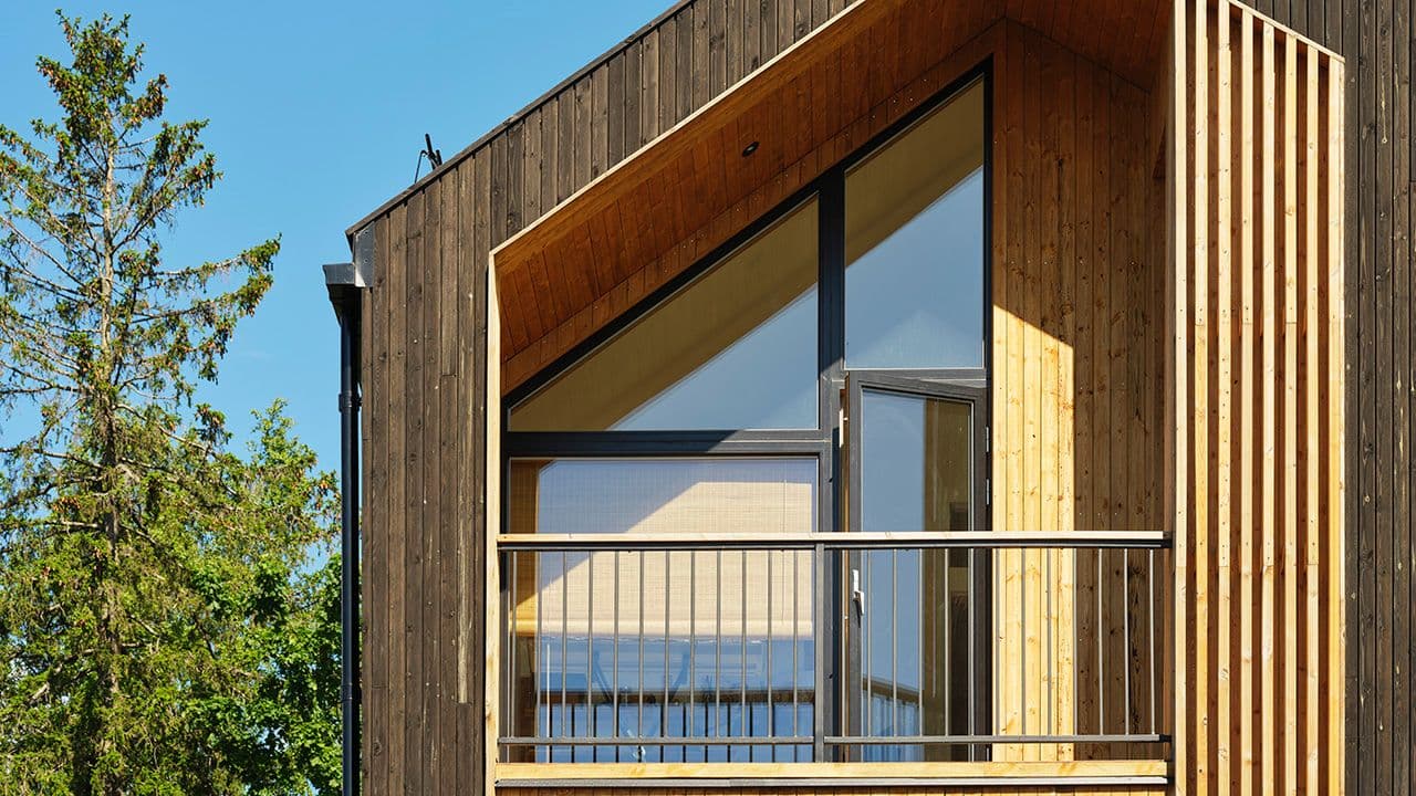 Nærbilde av hus med balkong og MøreRoyal kledning i brun og oker.