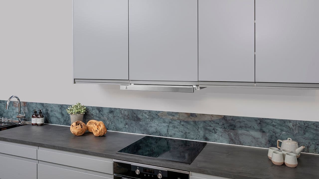 Uttrekksventilator på lyst kjøkken med mørk benkeplate.