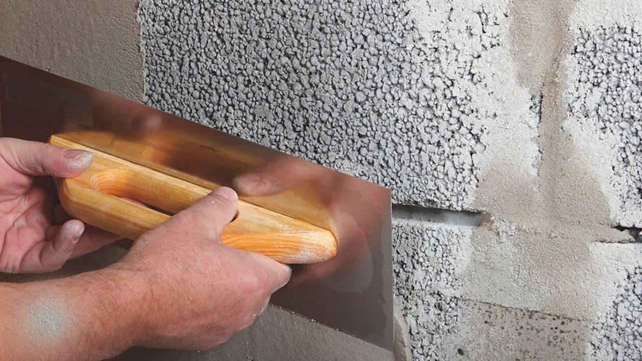 Person som reparerer mur med sparkel og sparkelspade.