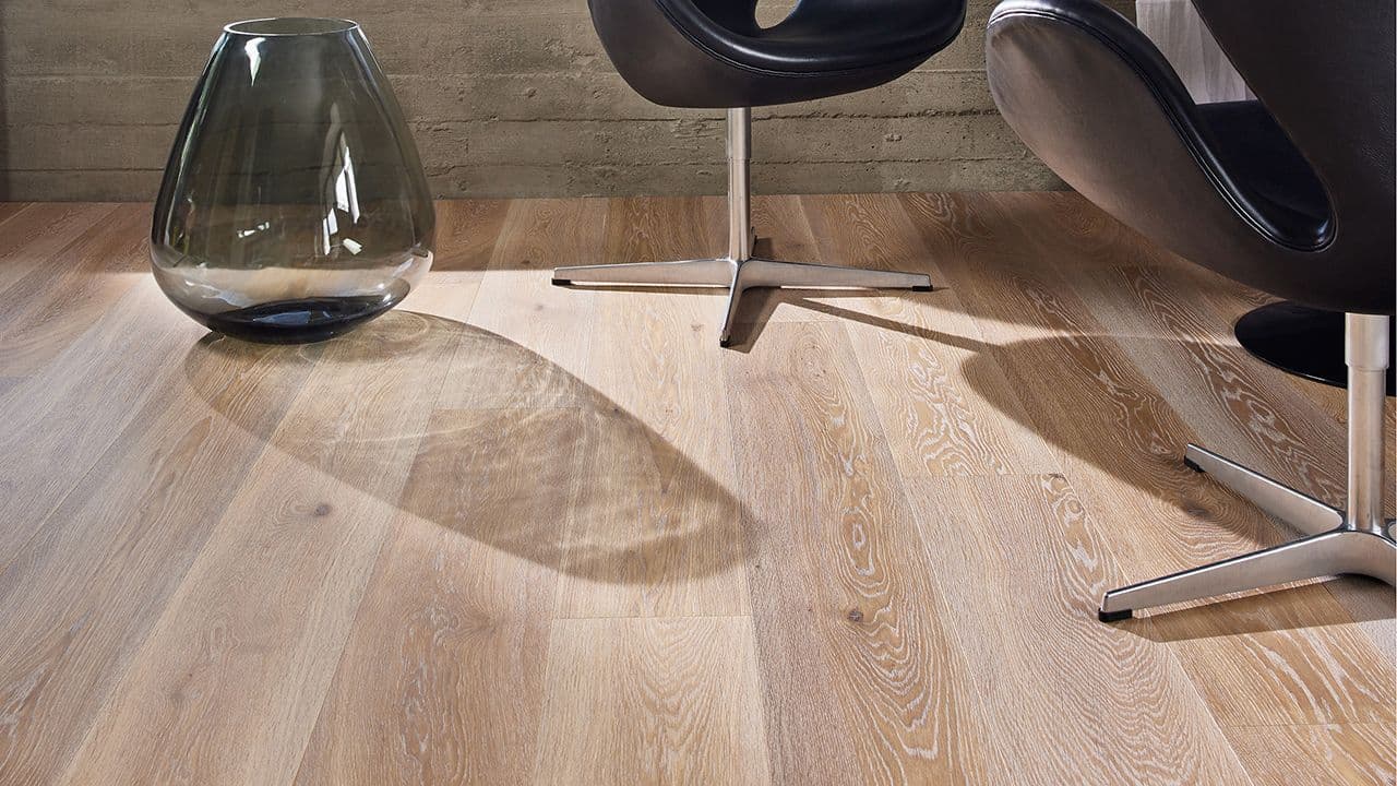 1-stavs parkettgulv i stue med to svarte lenestoler og stor vase på gulvet.