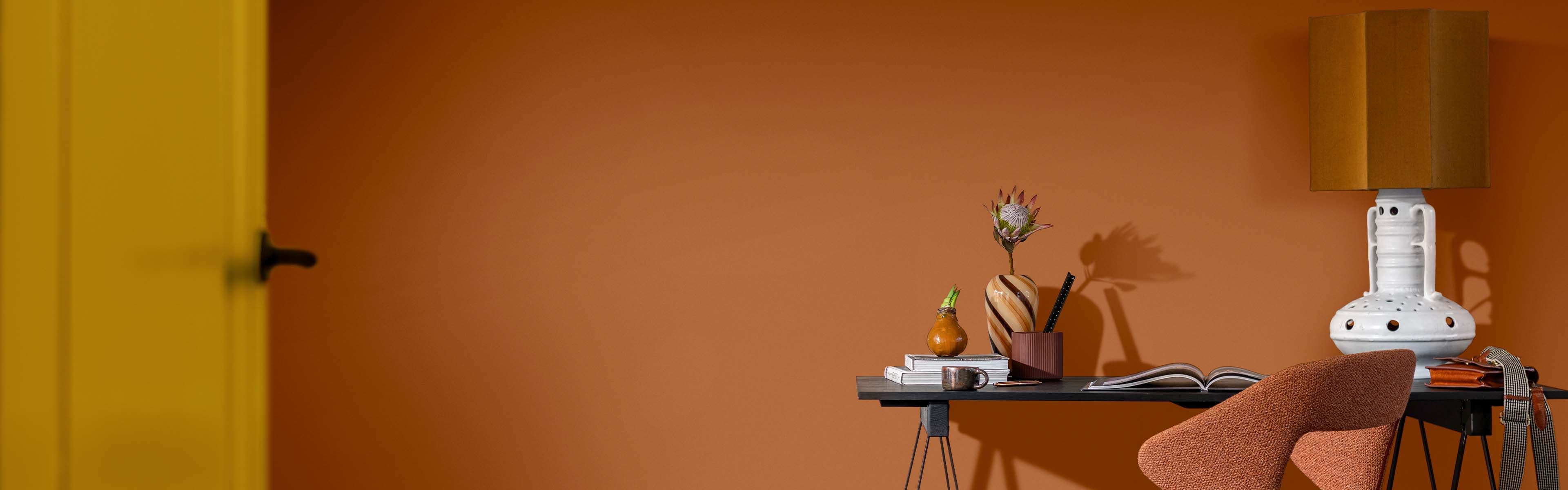 Hjemmekontor med orange vegg og gul dør.